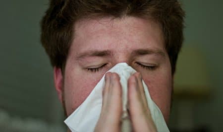A guy blowing his nose due to HIV symptoms.