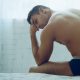 Muscular young man sitting on a bed in his underwear.