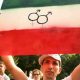 A photo of a man holding up an Iranian flag and equal rights logos.
