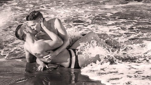 A photo of a gay couple kissing on the beach.