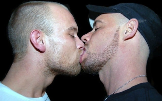 A photo of two young men kissing.