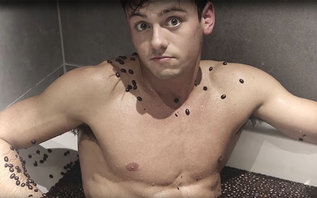 This is a photo of Tom Daley in a bathtub filled with coffee beans.