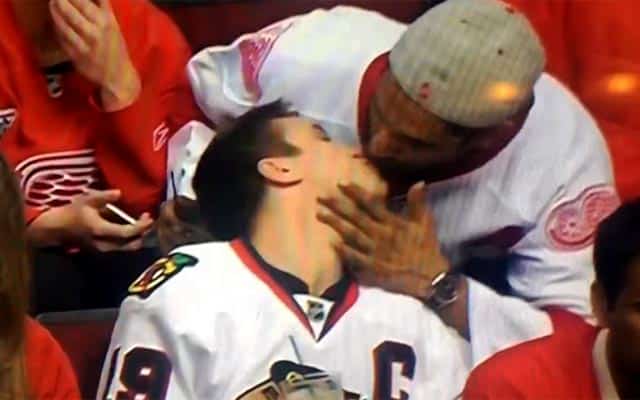 This is a photo of two men at a hockey game kissing.
