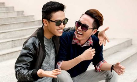 Two Asian men sitting on steps and laughing.