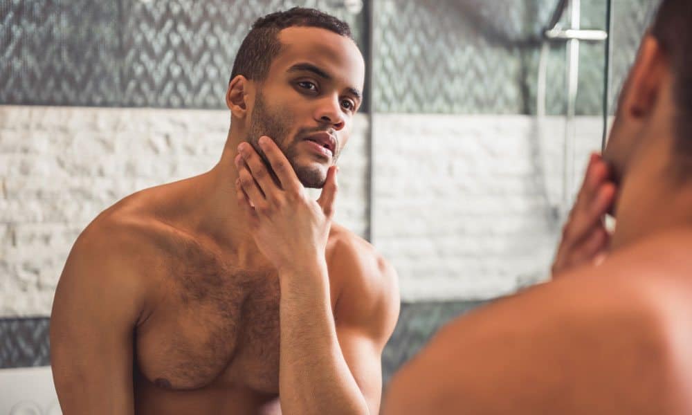 Shirtless man with beard looking in the mirror