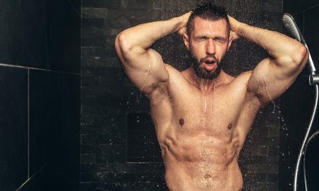 Attractive muscular man taking a shower, details of man in rainshower.