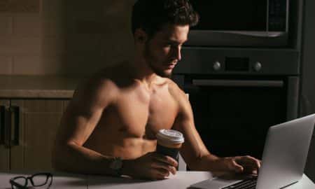 A shirtless young man working on a computer