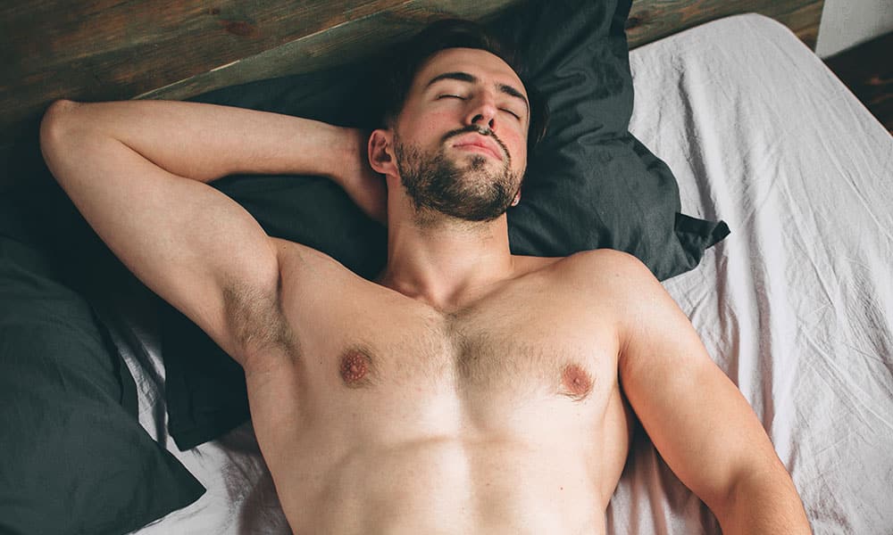 Portrait of a fit male model asleep in luxurious bedroom