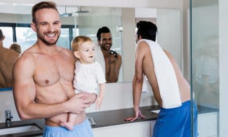 Smiling gay couple with child in the bathroom