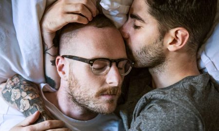 Gay couple lying on bed at home