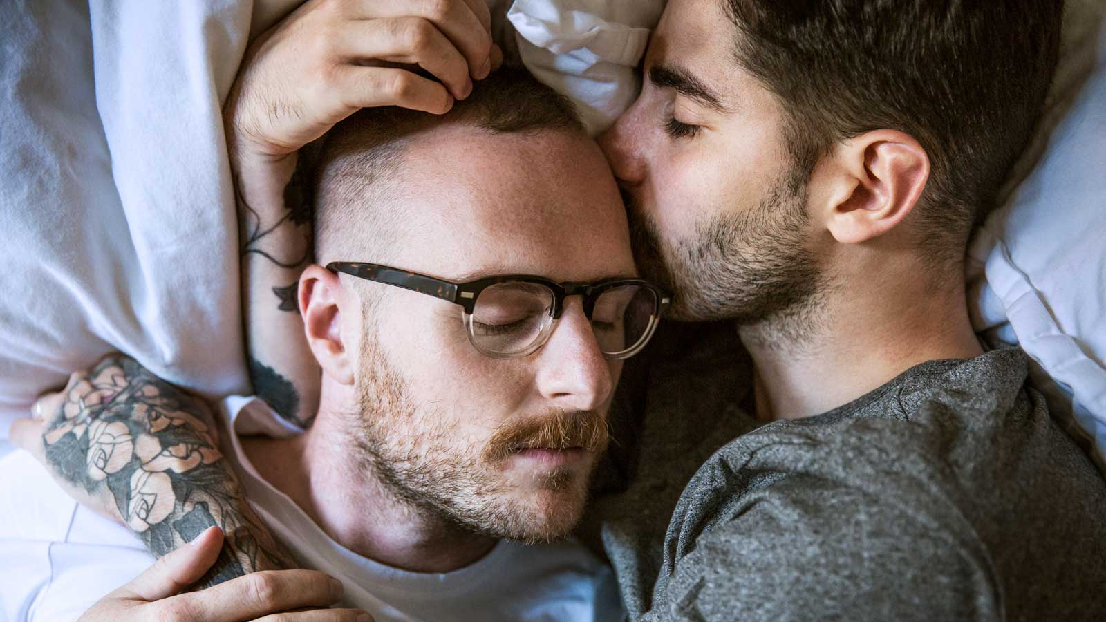 Gay couple lying on bed at home