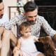 Gay couple with daughter and dog on balcony using digital tablet