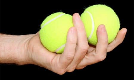 Man holding two tennis balls in one hand