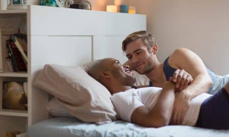 Gay couple lying in bed together, hugging