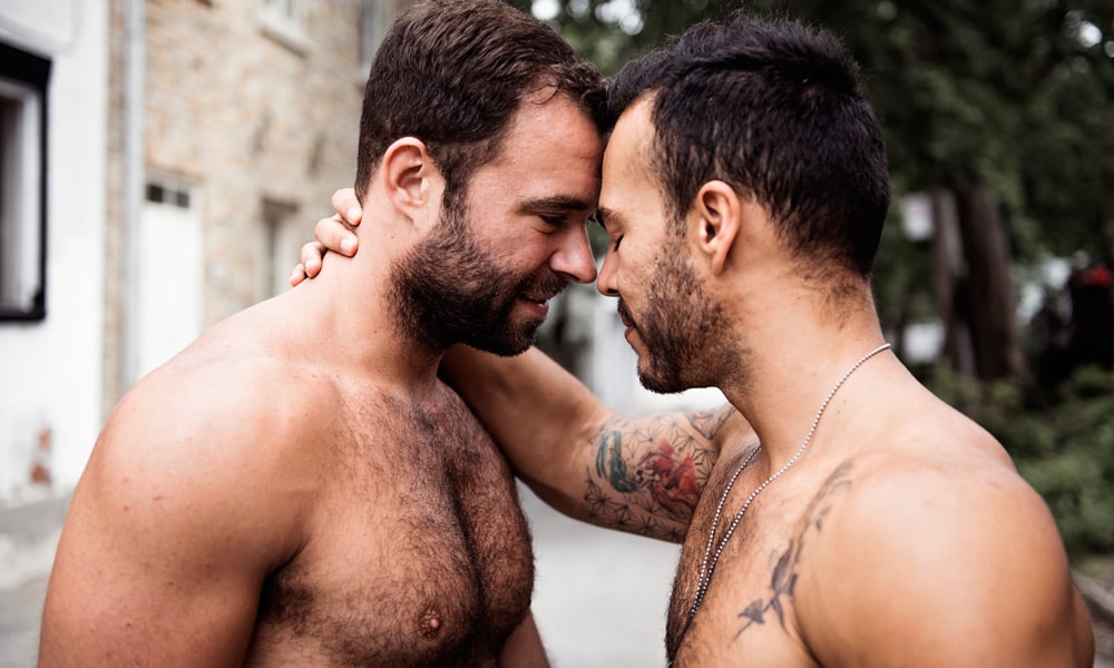 这是两个赤膊上班并要亲吻的男同性恋者的照片。 