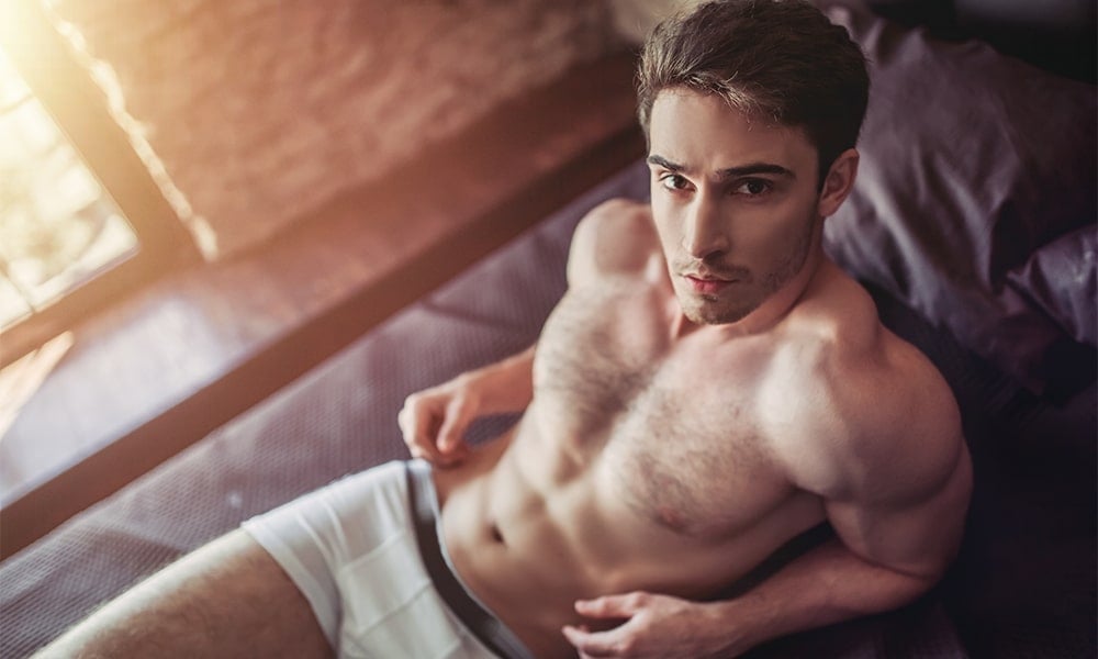 Handsome sporty young man in underwear is lying on bed
