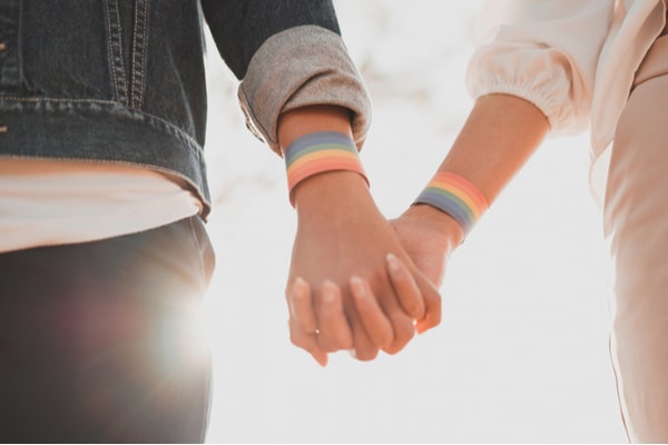 couple holding hands with rainbow bracelets