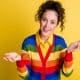 female in rainbow sweater with questioning hands and expression