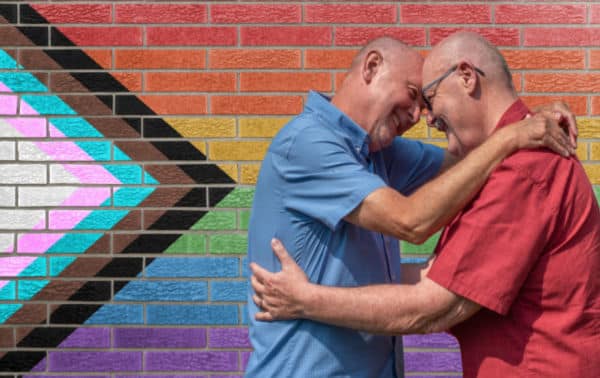 older male couple embracing and smiling