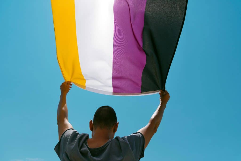 Close-up of a young person waving a non-binary pride flag