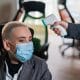 Business woman in medical mask has body temperature measured with electronic thermometer at workplace in office.