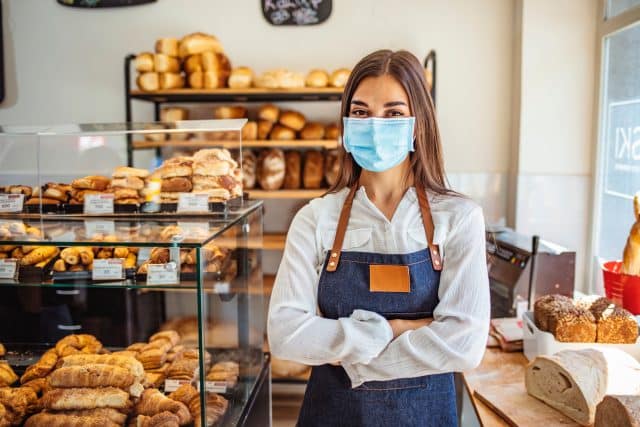 Woman working at a bakery wearing a face mask to avoid the coronavirus.