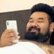 Asian man shirtless with smartphone in bed